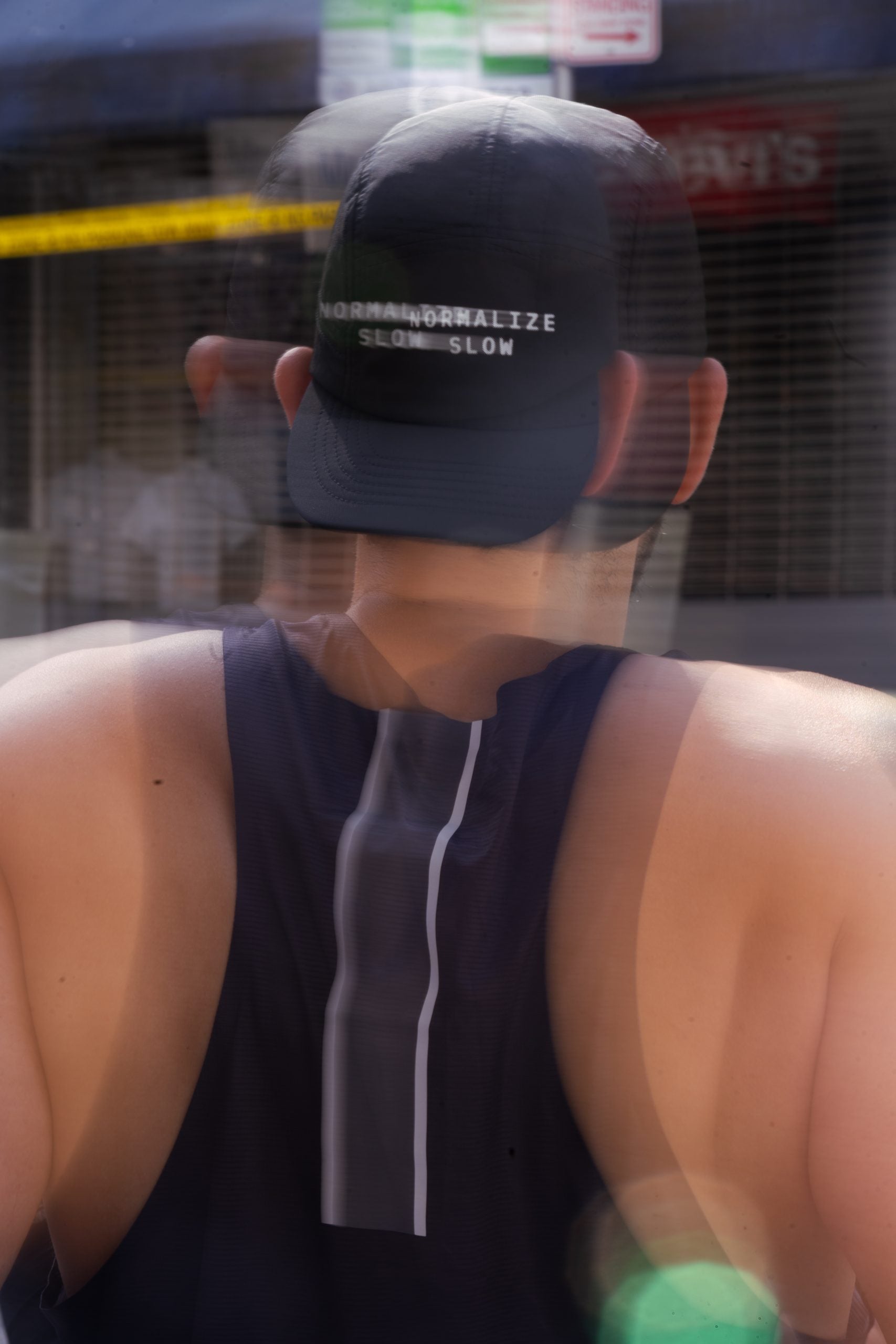 A motion-blurred shot from behind of a man wearing the Normalize Slow Cap outdoors.