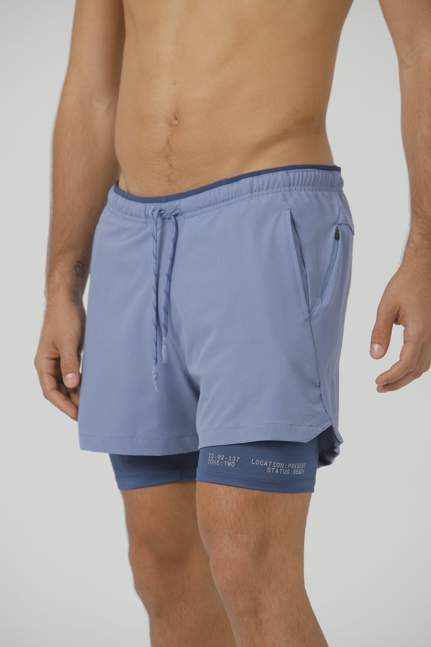 A model in the Blue Mirage Drift Shorts, a slate blue, showing the drawcord waist and inner liner.