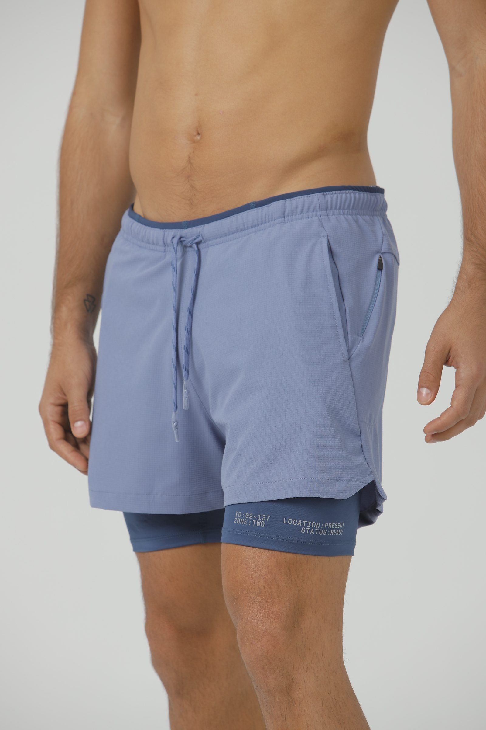A model in the Blue Mirage Drift Shorts, a slate blue, showing the drawcord waist and inner liner.