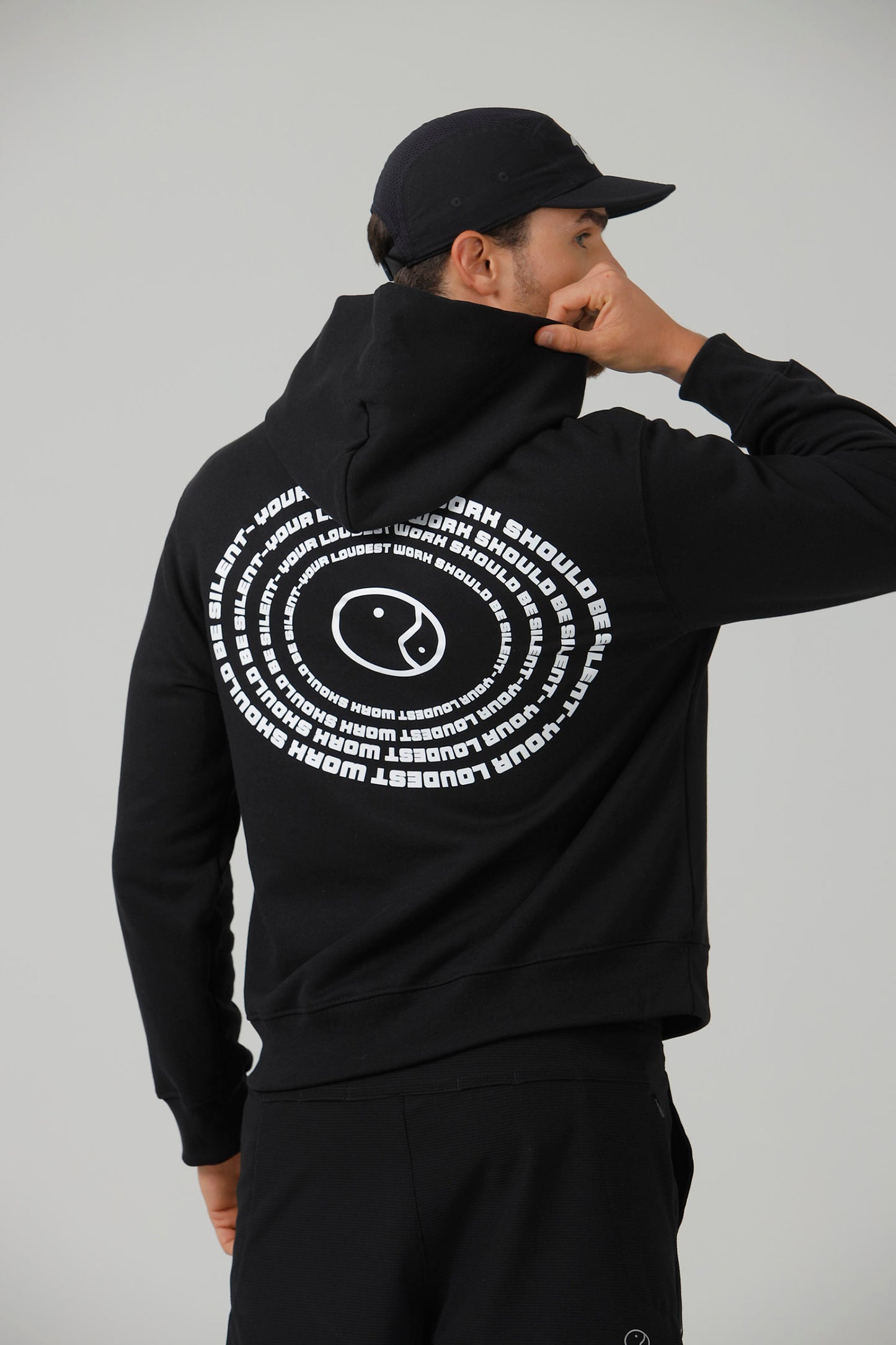 The back of the black Quiet Hoodie, showing the spiral of text printed across the shoulders.