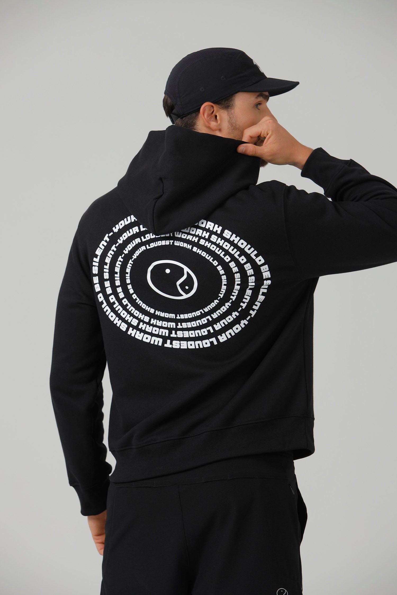 The back of the black Quiet Hoodie, showing the spiral of text printed across the shoulders.