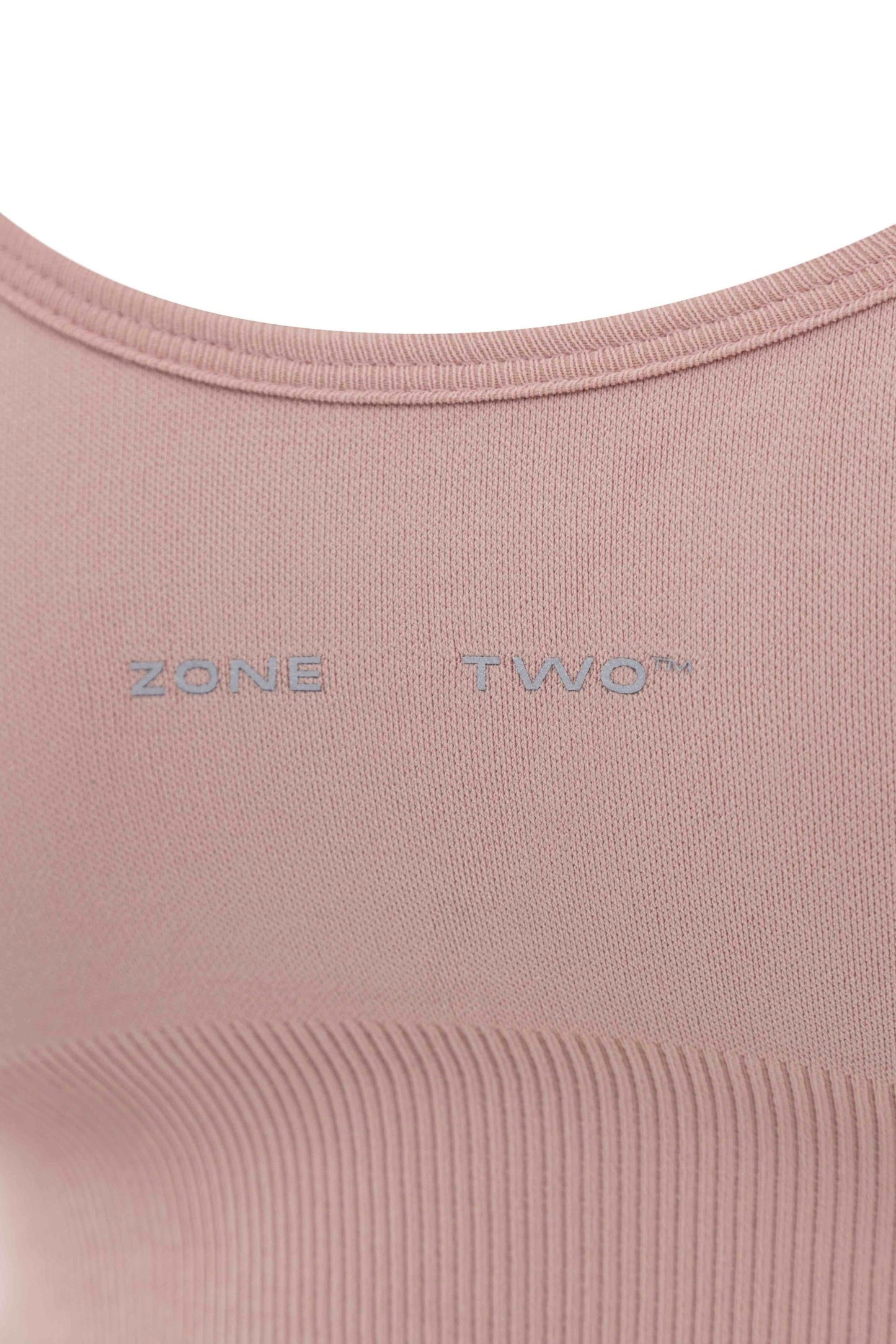 Close-up of the pink Top Flow Racerback showing the Zone Two wordmark and ribbed underband.